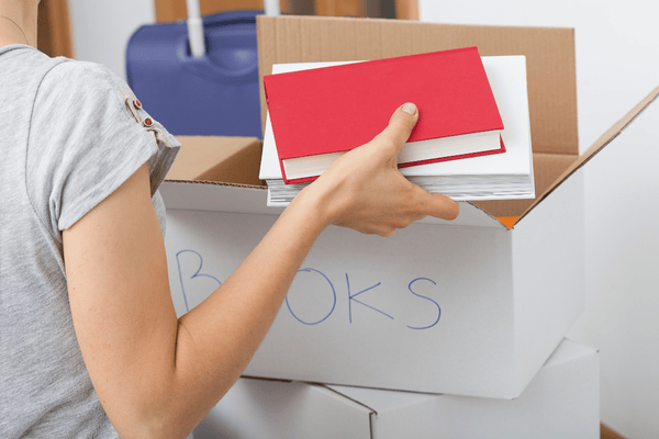 arranging-books-by-size-mngmovers storing books inside a box by size in preparation before moving.