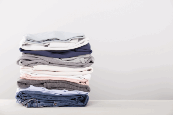 clothes-for-packing-mngmovers Multi colored clothes that are folded in a single stack.