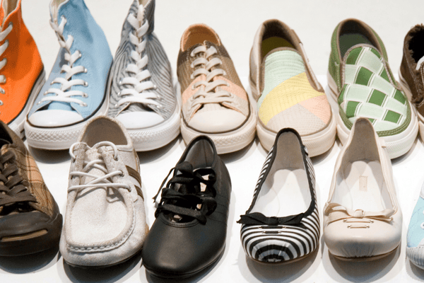 how-to-sort-shoes-mngmovers A variety of colorful and stylish women’s shoes, including sneakers, flats, and casual slip-ons, neatly arranged in rows on a white background.