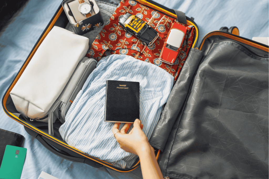 Open suitcase neatly packed with clothes, toiletries, and a passport being placed inside by hand—illustrating efficient travel packing strategy.