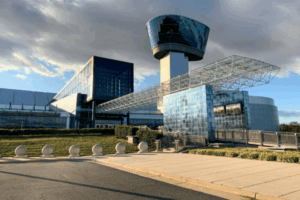 Modern exterior of the Steven F. Udvar-Hazy Center in Chantilly, VA, featuring glass architecture, a control tower, and a pedestrian walkway under a dramatic sky.