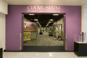Entrance to the CIA Museum with a purple sign reading "Inform • Instruct • Inspire," showcasing intelligence history exhibits and military artifacts inside.