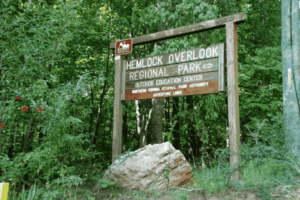 Entrance sign to Hemlock Overlook Regional Park in Clifton VA, surrounded by lush greenery and forest trails—part of the Northern Virginia Regional Park Authority.