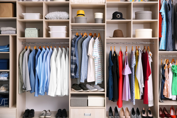 how-to-pack-clothes-for-moving-mngmovers-1 Organized closet with color-coordinated clothing, shoes, and storage boxes—perfect reference for how to prepare and pack clothes for moving.