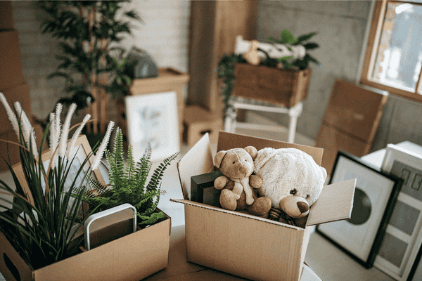 why-moving-is-so-stressful-2-mngmovers Boxes filled with personal items and toys in a cluttered space, representing how moving disrupts daily routines and home organization.