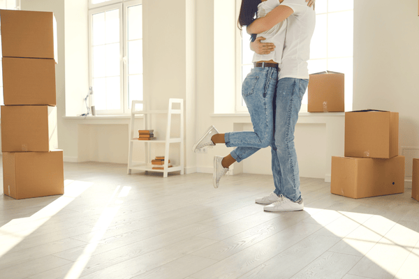 improper-disposal-of-mattress-mngmovers (3) Happy couple embracing in a bright new home surrounded by moving boxes, symbolizing the excitement of moving into a new place.