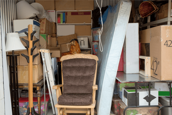 improper-disposal-of-mattress-mngmovers (4) Overfilled storage unit with stacked boxes, furniture, and a used mattress, illustrating clutter and the need for proper disposal or organized storage during a move.