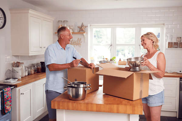 improper-disposal-of-mattress-mngmovers (5) Smiling couple packing kitchen items into cardboard boxes, showing how to pack household items efficiently when preparing for a move.