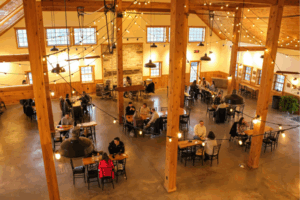 Rustic tasting room with wooden barrels and guests enjoying cider flights.
