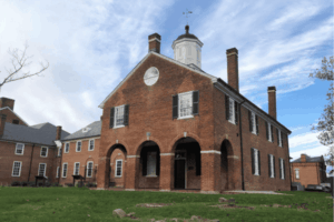 Historic brick courthouse in Old Town Fairfax VA under a partly cloudy sky, showcasing colonial architecture and a well-kept green lawn.