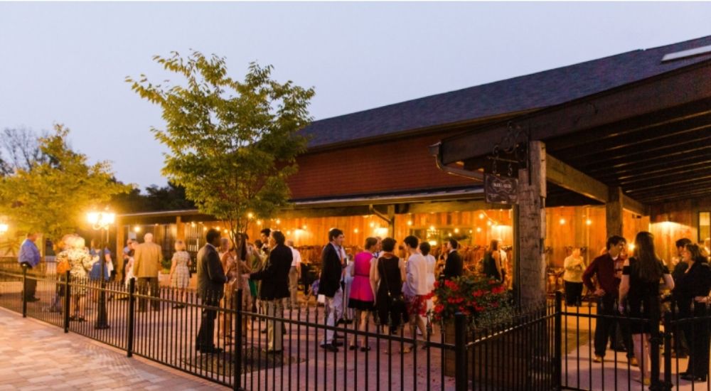 Guests mingle at The Winery at Bull Run in Virginia during an evening event with string lights and music.