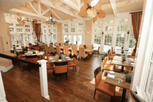 Elegant dining room at Trummer’s in Clifton VA featuring tall windows, wood floors, and upscale seating — a popular Main Street restaurant near antique shops and local boutiques.