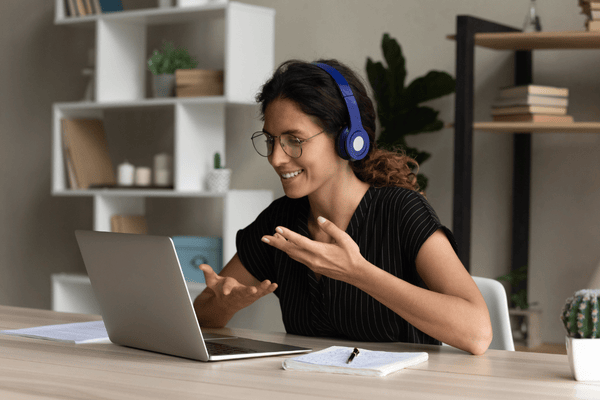 why-do-people-move-mngmovers-3 Woman wearing headphones having a video call on her laptop, representing how remote work influences moving decisions and location flexibility.